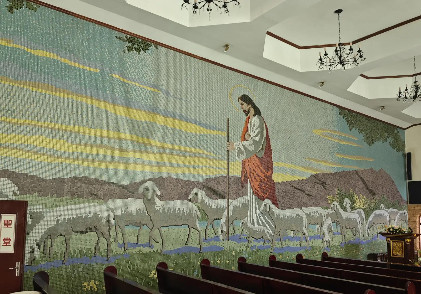 Mosaic of a shepherd in a red robe leading sheep across a green landscape.