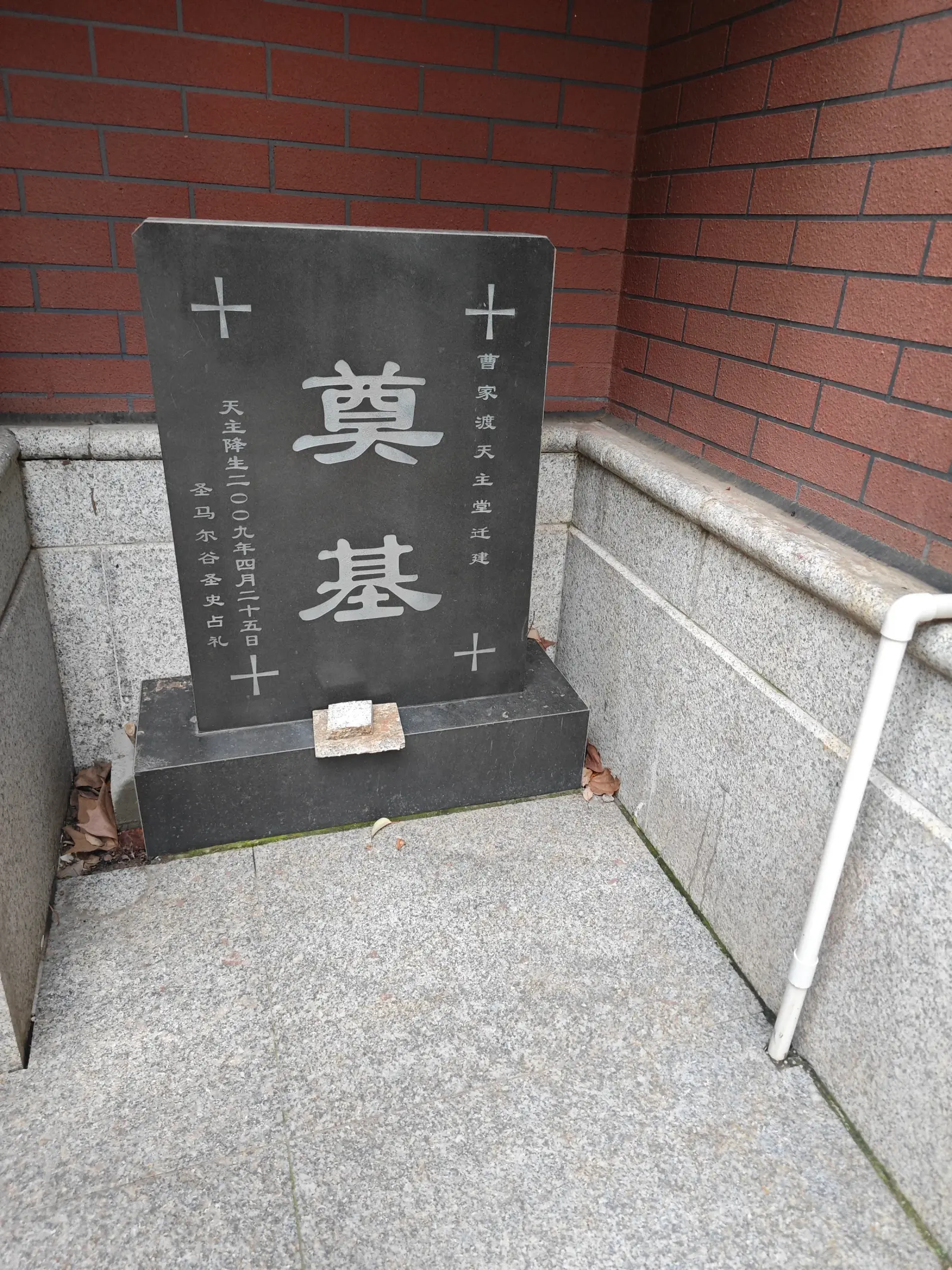 A black stone tablet with the characters for foundation stone, set in a brick and granite corner.