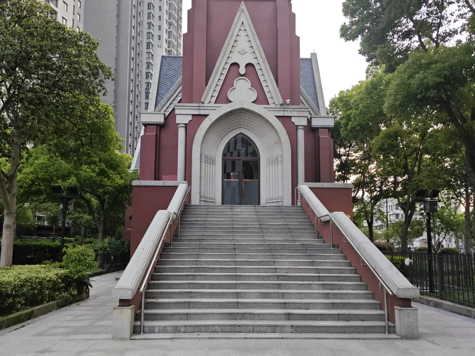 A wide flight of steps leading to a red-brick tower entrance with a pointed arch and gabled hood.