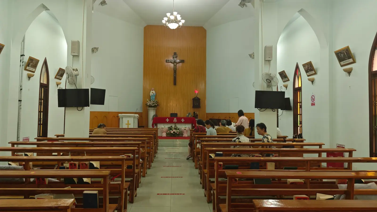 Church interior with wooden pews leading to an altar and a large crucifix.
