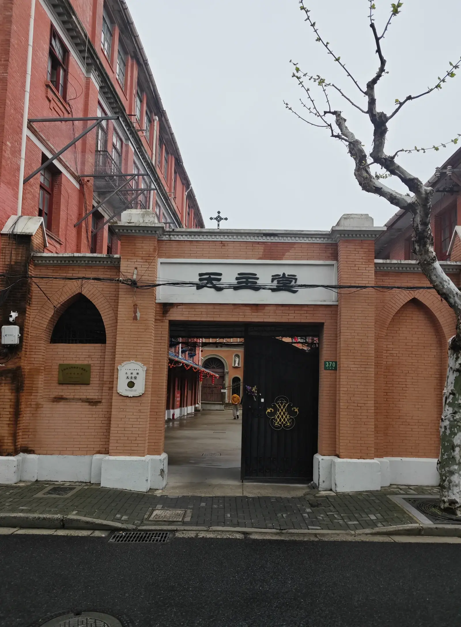 A red-brick gateway with a lintel bearing Chinese characters and a path leading into a compound.
