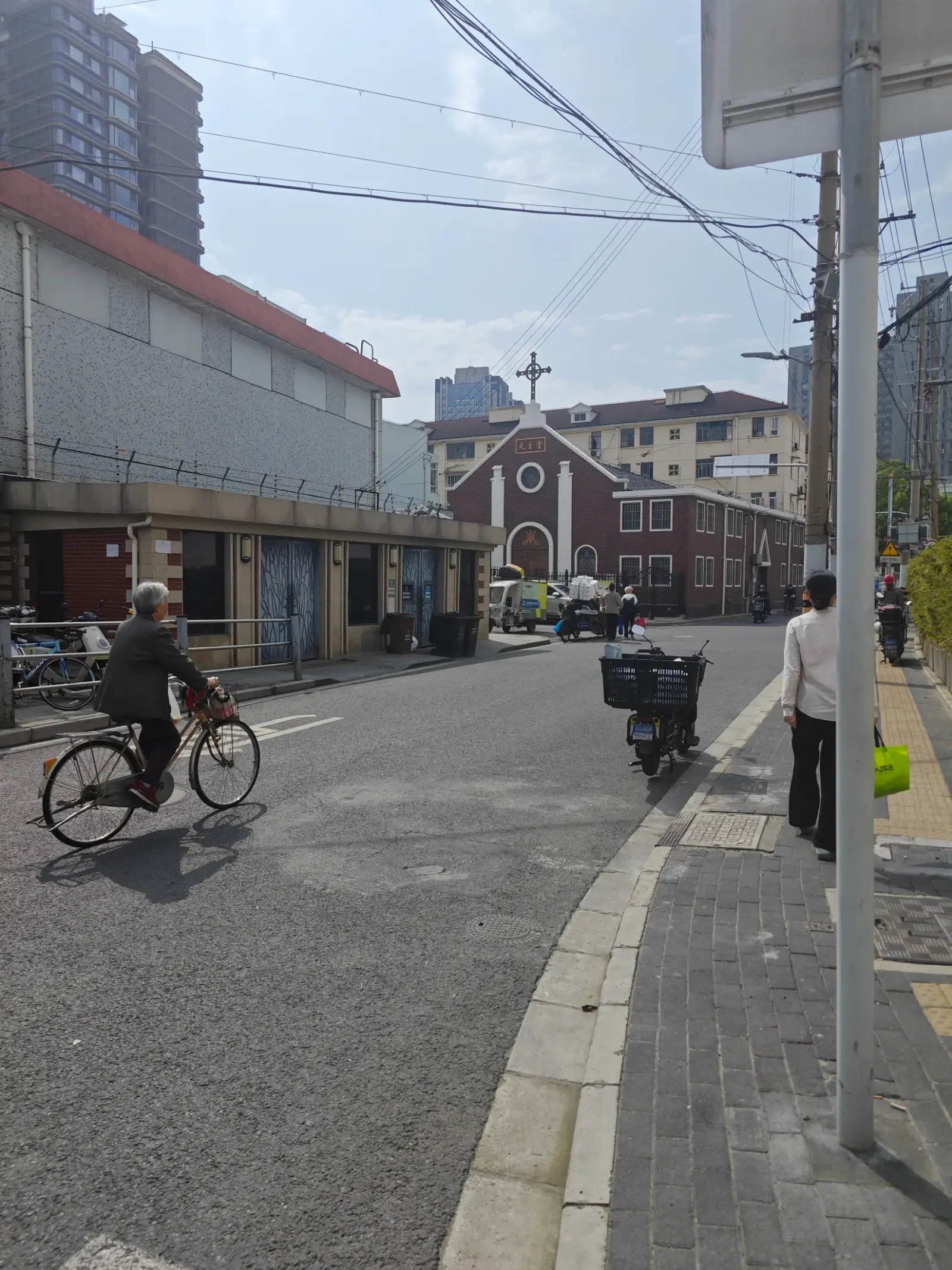 A narrow street with a cyclist and the red-brick church visible in the distance.