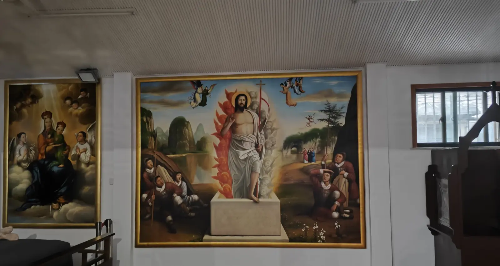 A large framed painting of a risen figure in a landscape on a white church wall.