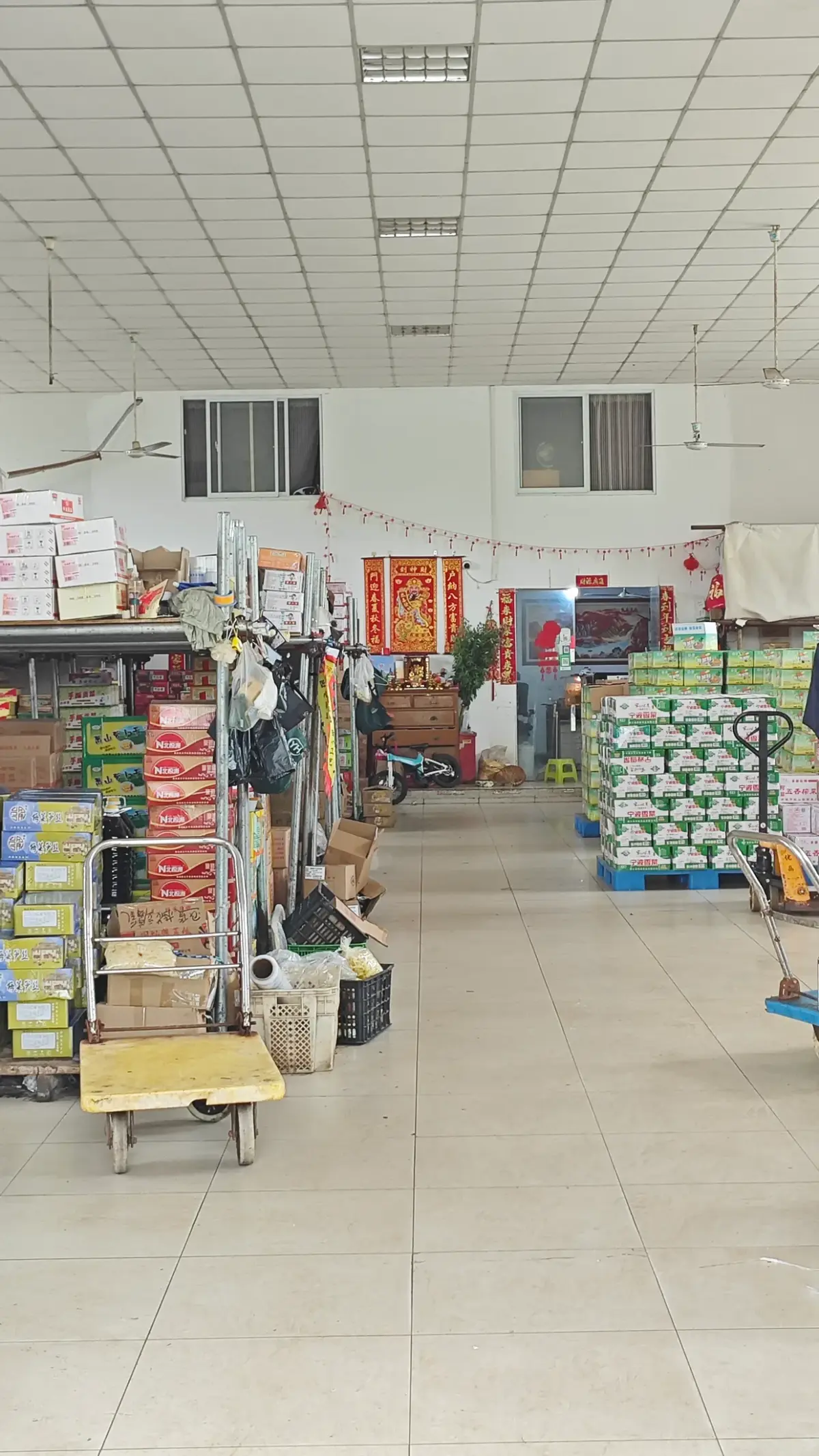 A long tiled hall lined with shelves of boxed goods.