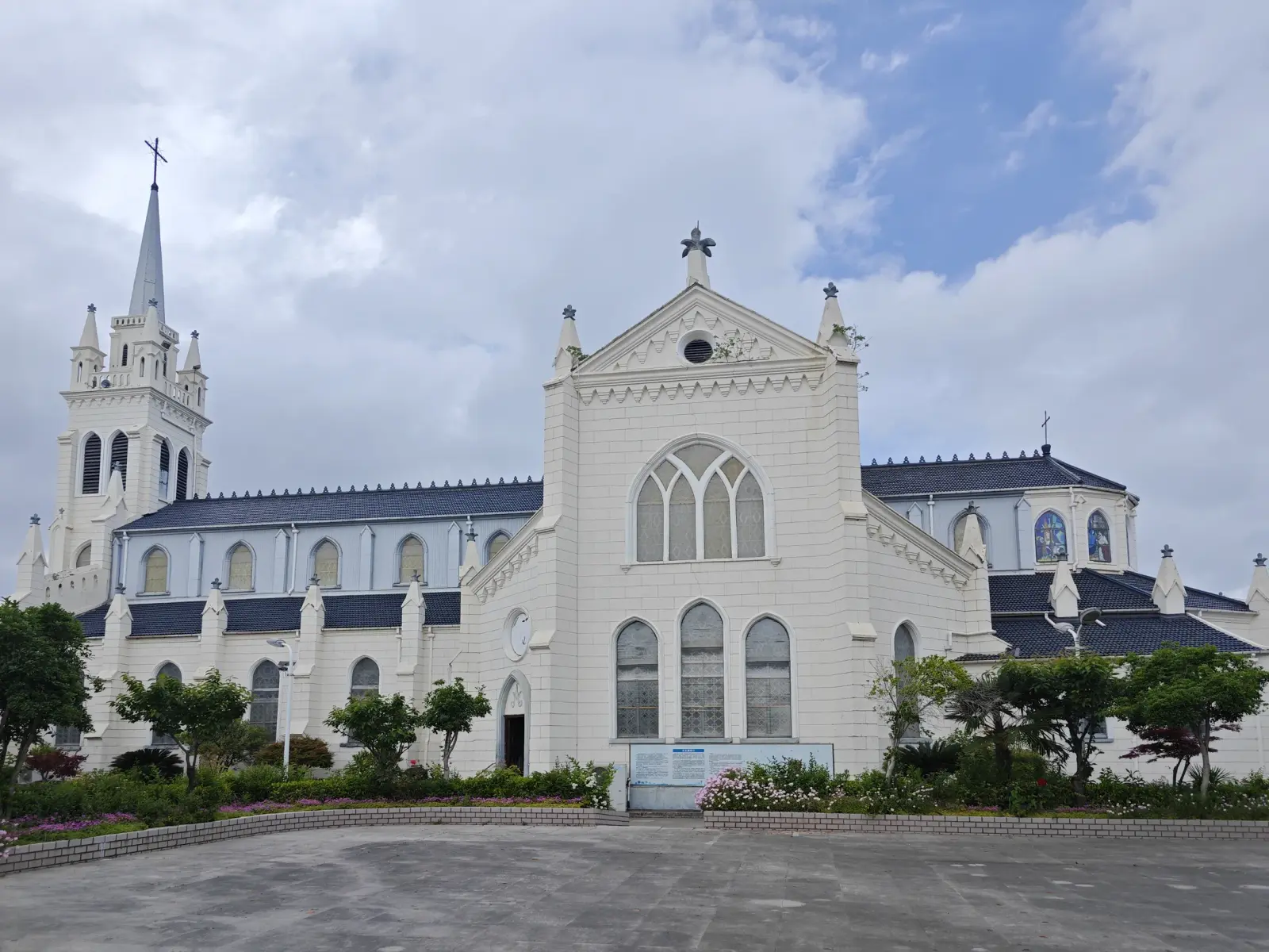 A large cream Gothic church with a spired tower at left, a central pointed gable with traceried window, and a blue-grey roof.