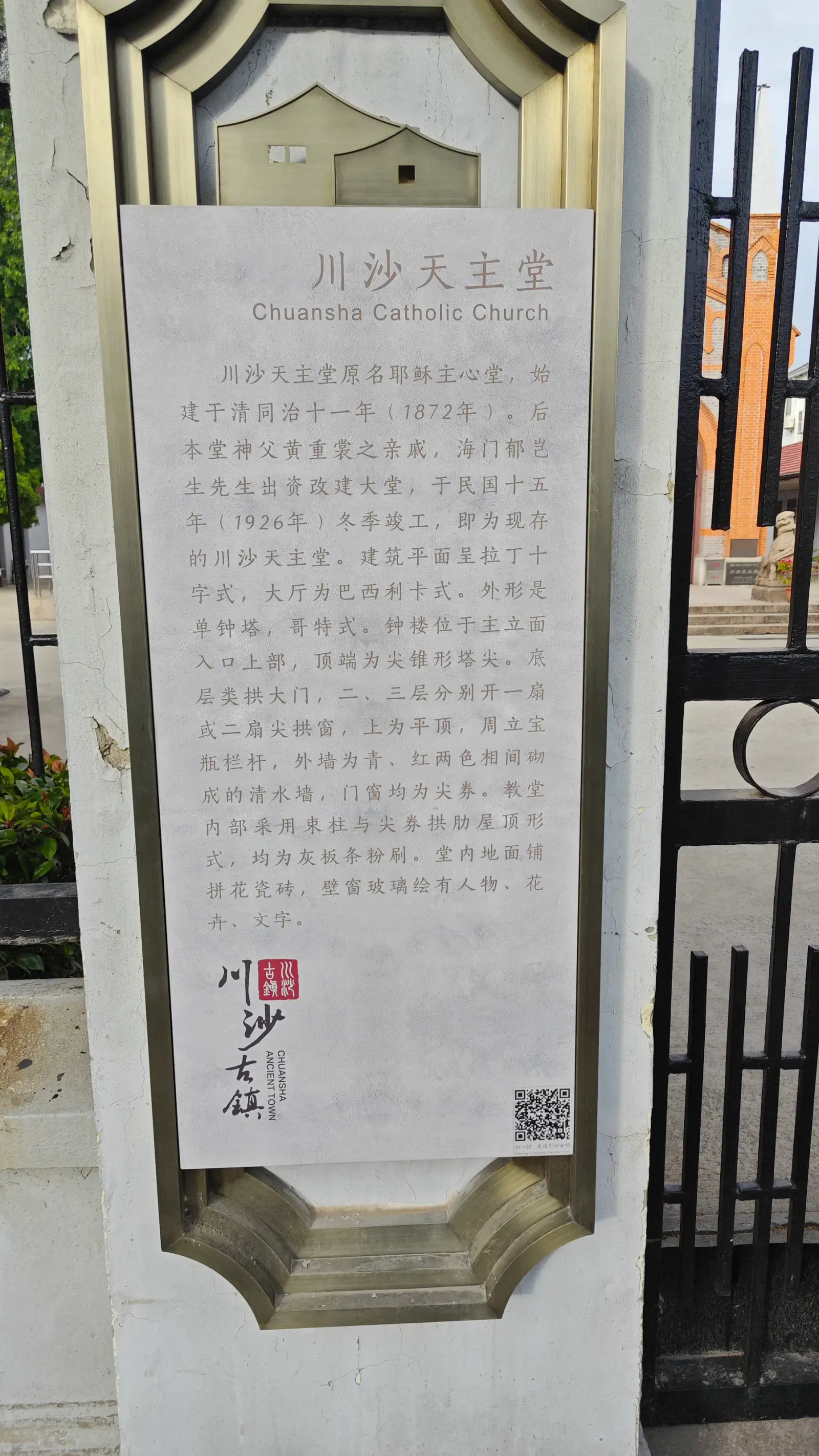 A pale stone information board with Chinese text and the English title Chuansha Catholic Church, mounted on a gate post.