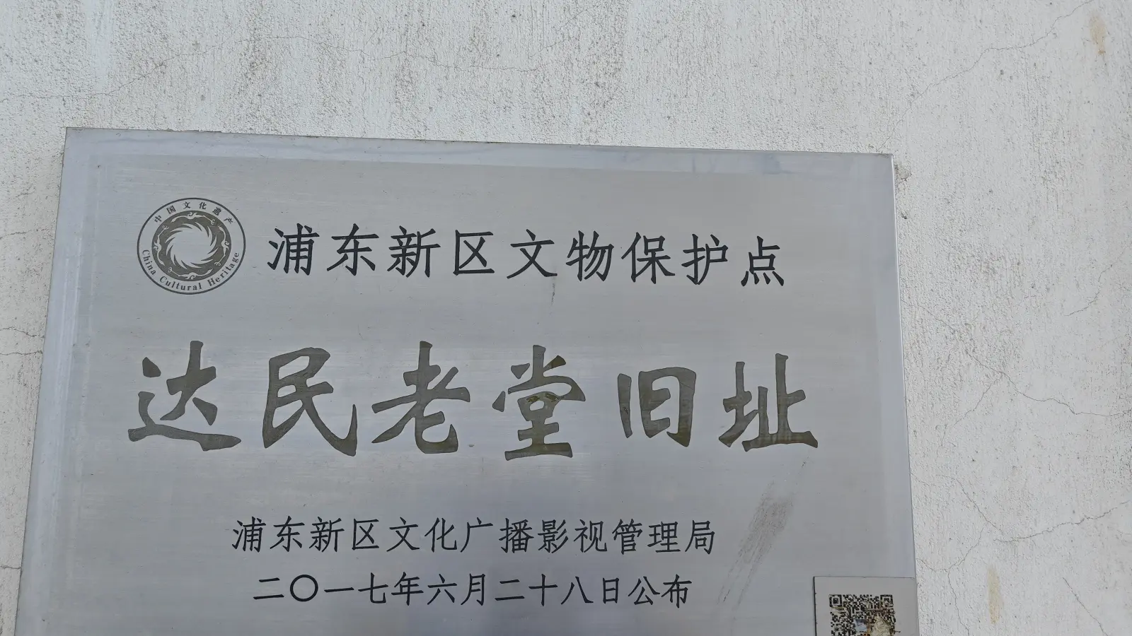 A grey metal plaque with Chinese text naming the former church site as a Pudong cultural relic protection point.