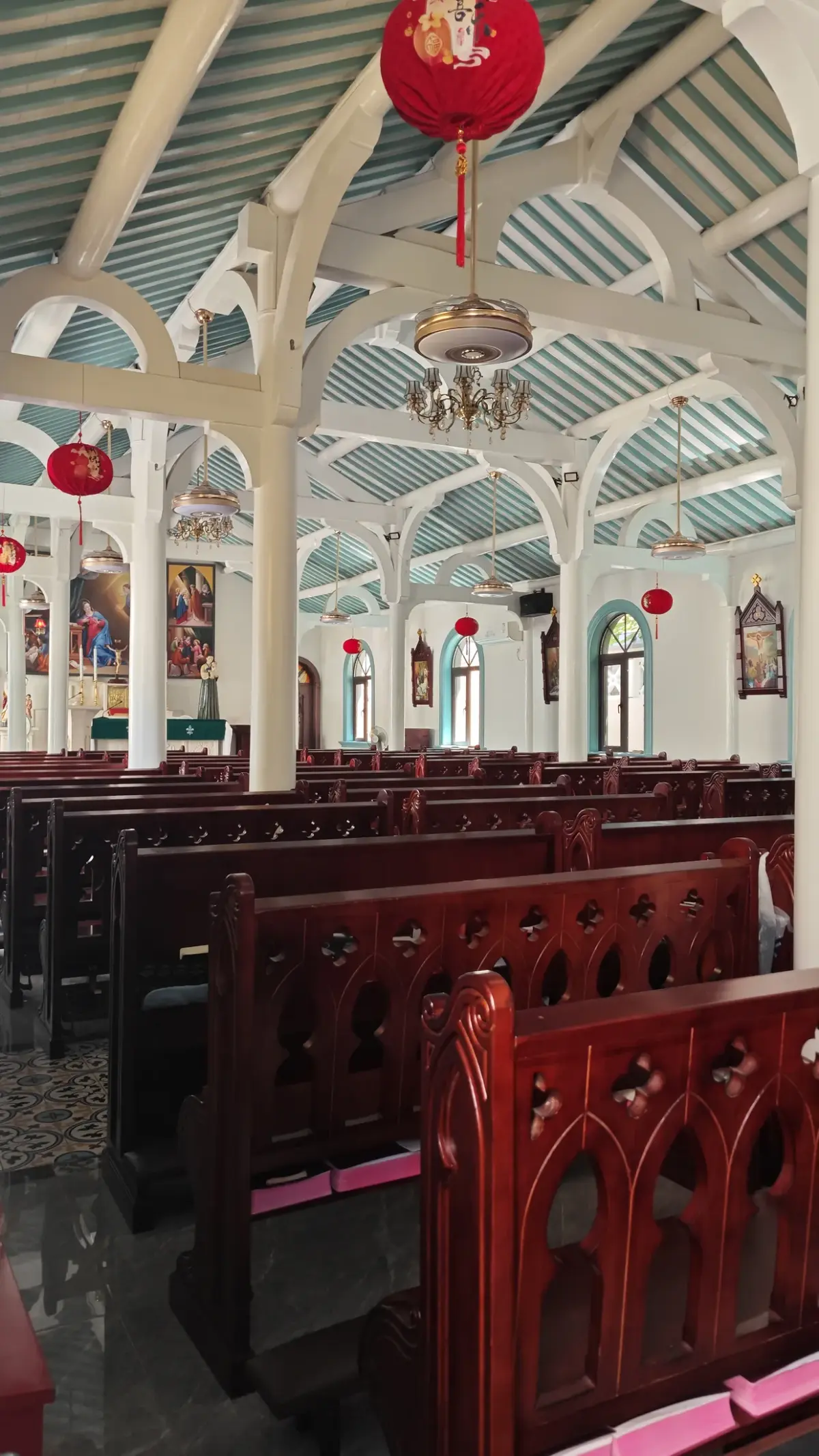 Rows of red pews below white trusses and a red lantern inside the church.