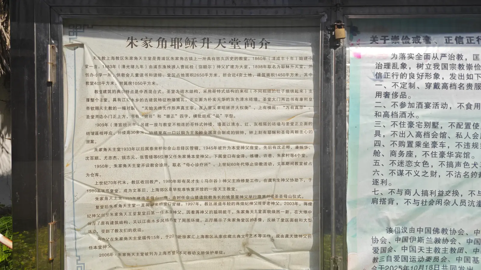 A glass-fronted notice board holding a long printed Chinese text and a second notice beside it.