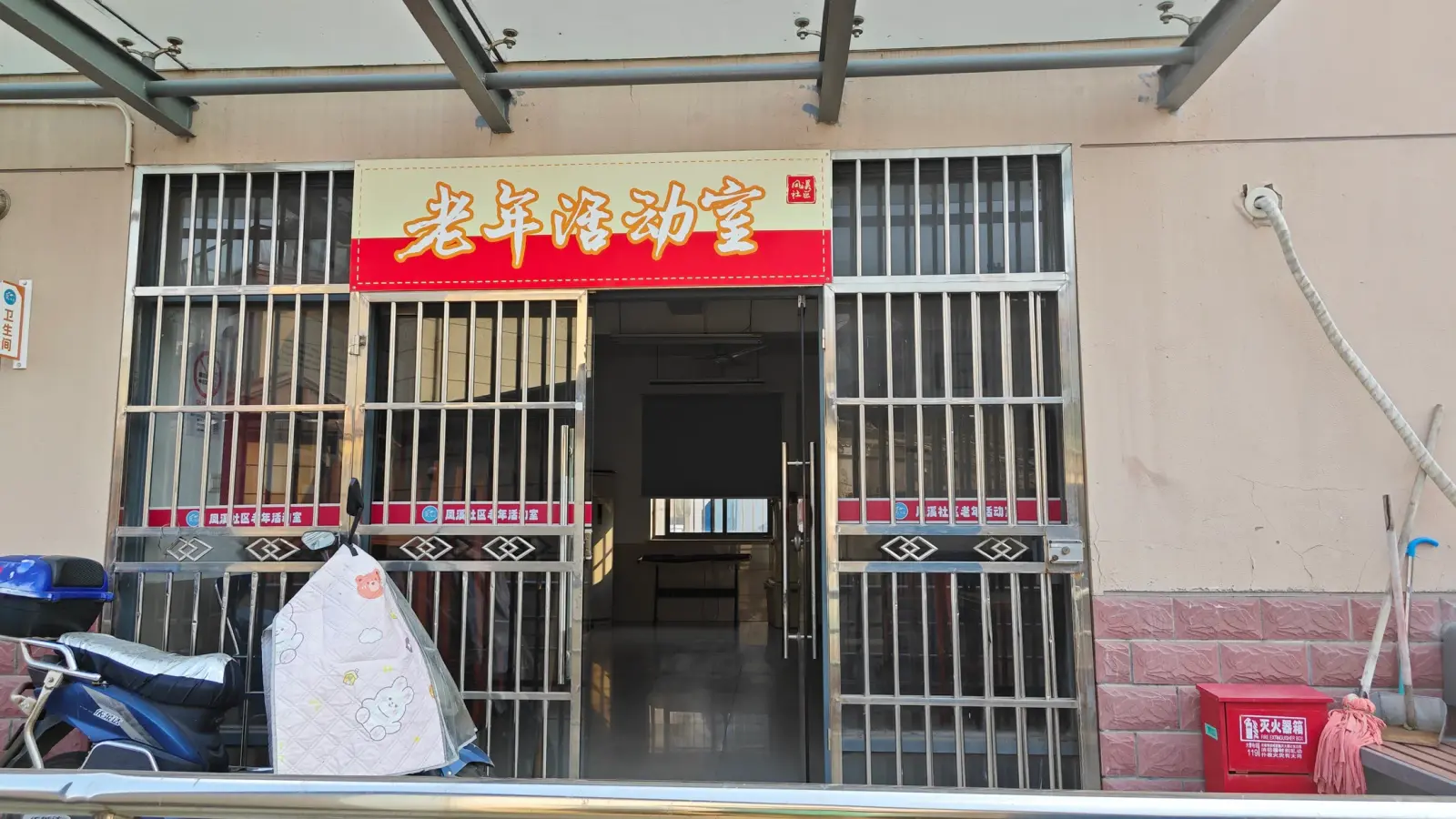A barred glass entrance under a red sign with gold Chinese characters.