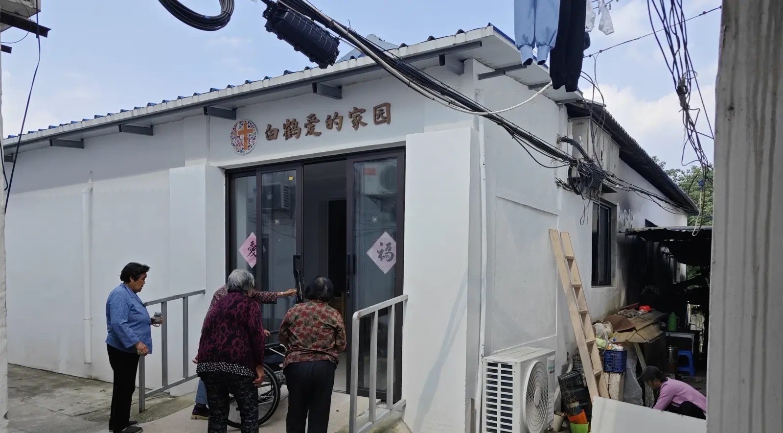 A small white prefabricated building with a glass door and a Chinese sign, with three people standing at the entrance.