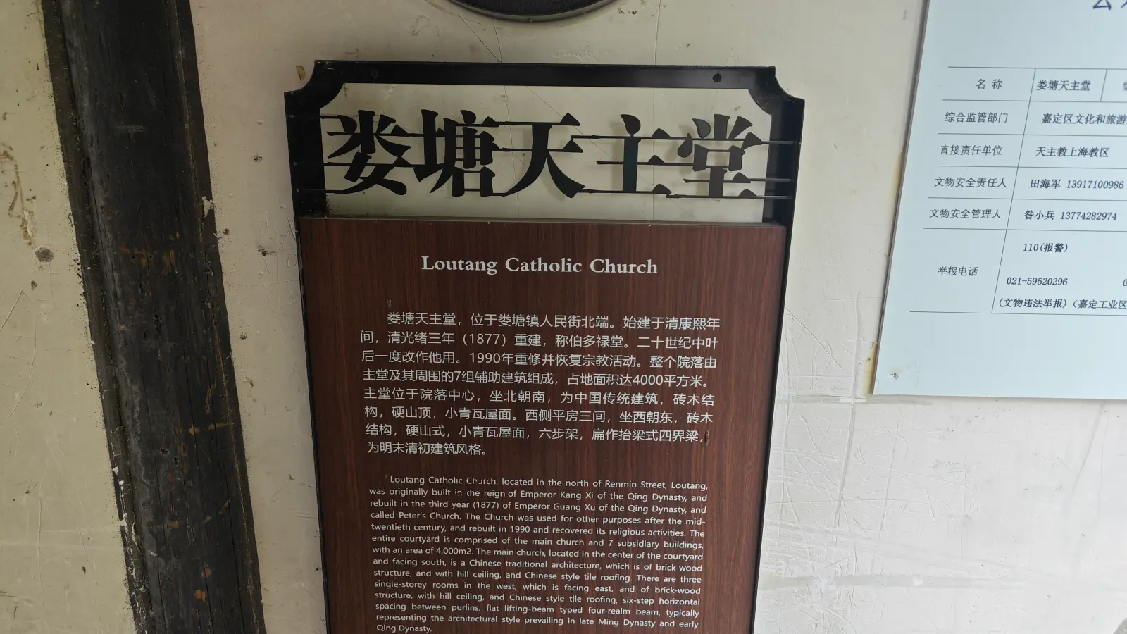 A brown wall plaque with Chinese and English text under the title Loutang Catholic Church, next to a pale information panel.