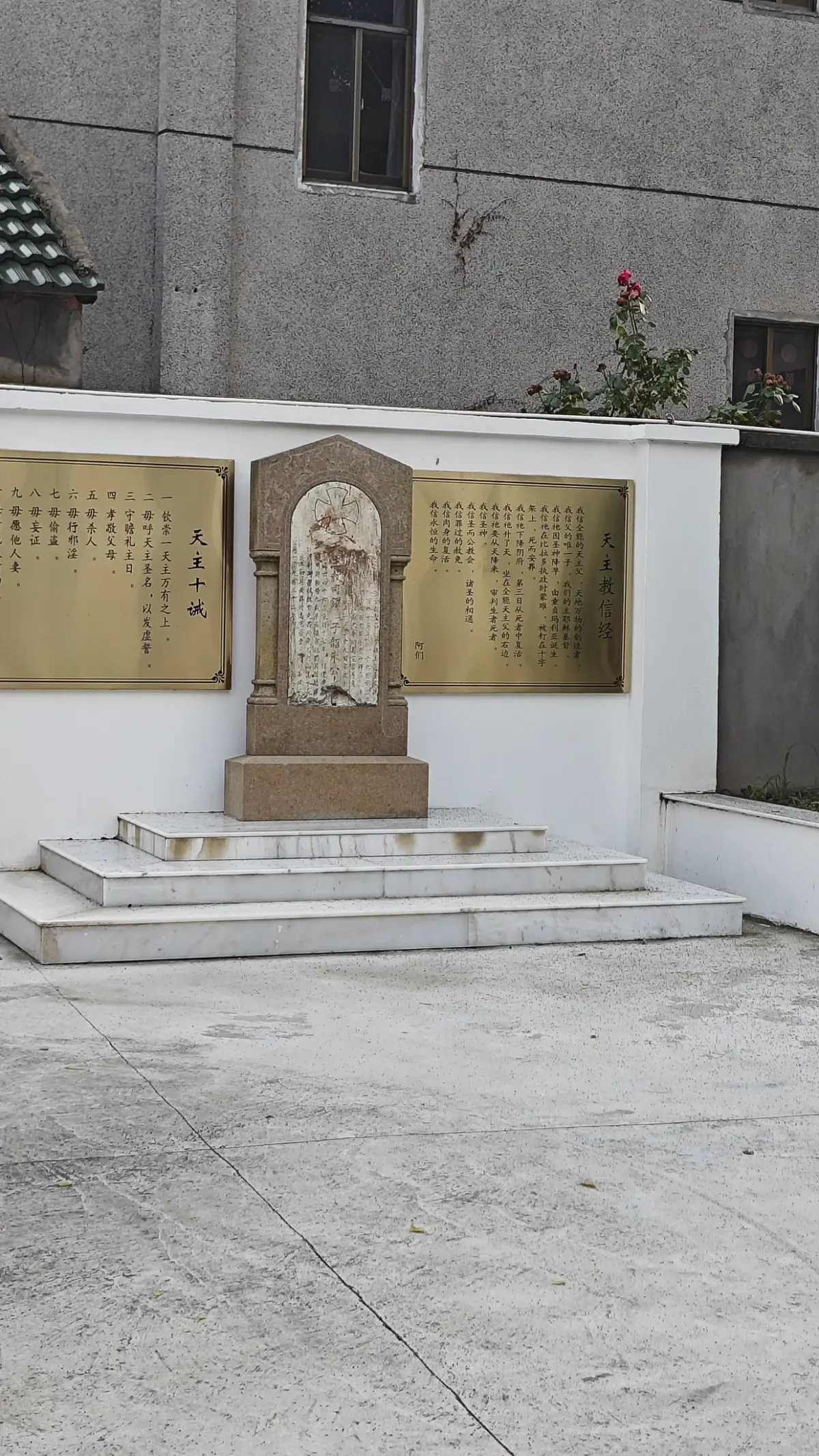 Courtyard shrine with a central statue niche flanked by two gold inscription plates.