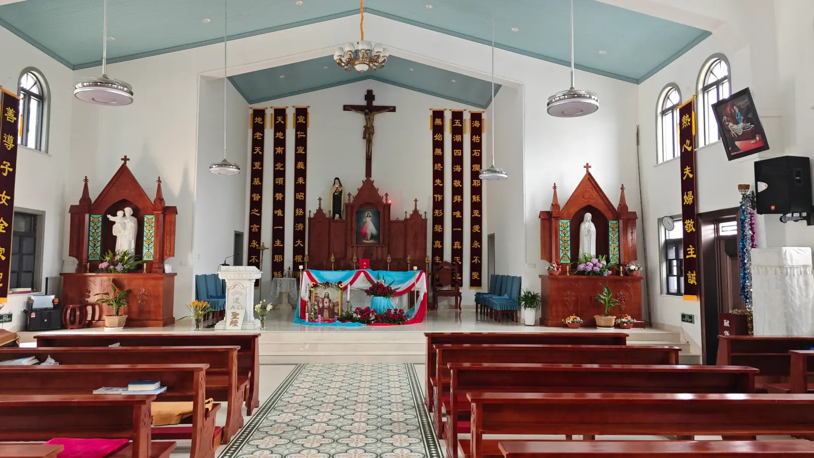 Altar with a crucifix and two carved side altars, with Chinese couplets on red banners.