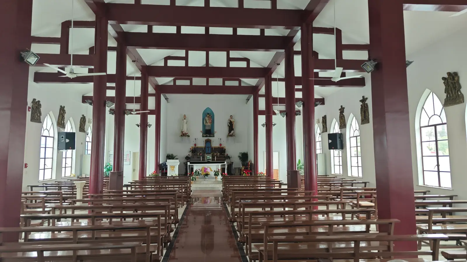 Interior of the church showing red timber columns, pews and a distant altar.