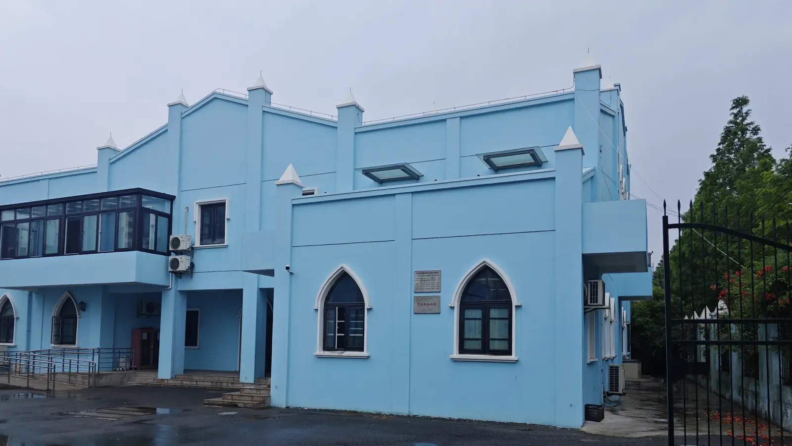A two-storey blue annex building with pointed arched windows.